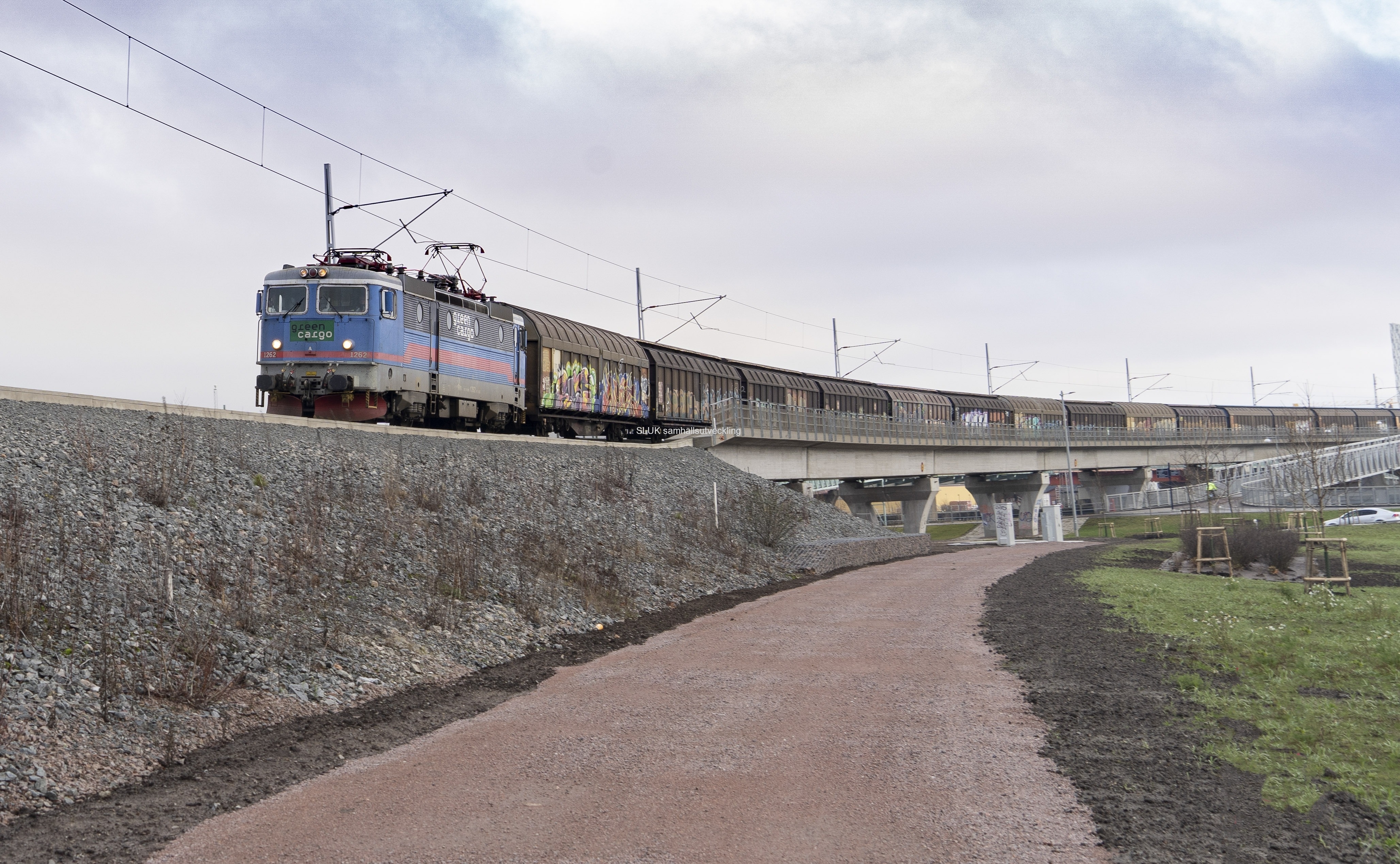 Hamnbanan går parallellt med Partihallsförbindelsen. Ett långt godståg är på väg mot Göteborgs Hamn.